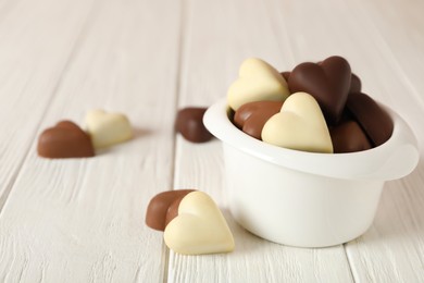 Beautiful heart shaped chocolate candies on white wooden table, space for text