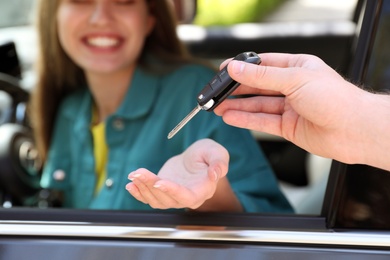 Image of Salesperson giving car key to customer, focus on hands