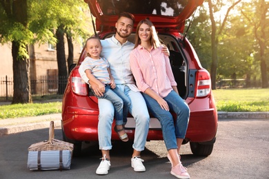 Photo of Happy family sitting in car's trunk outdoors