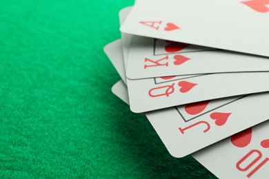 Hand of playing cards on green table, closeup. Space for text