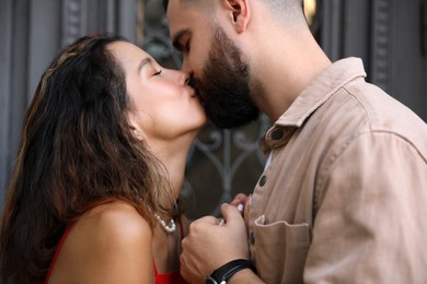 Happy young couple kissing near door outdoors, closeup
