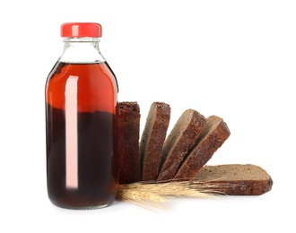 Photo of Bottle of delicious fresh kvass, spikelets and bread on white background