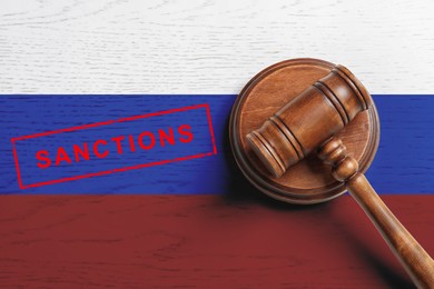 Judge's gavel on wooden background in color of Russian flag, top view. Concept of sanctions against Russia