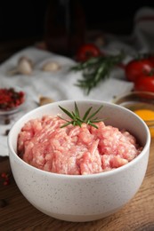 Raw chicken minced meat with rosemary on wooden table