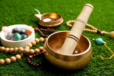 Composition with golden singing bowl on green grass, closeup. Sound healing