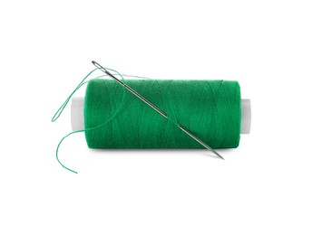 Spool of green sewing thread with needle isolated on white