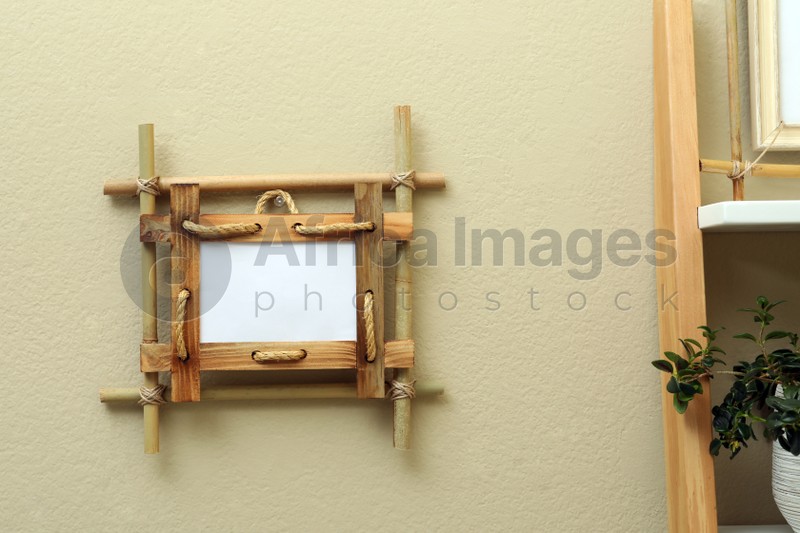 Bamboo frame on beige wall near rack