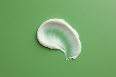 Sample of face scrub on green background, top view