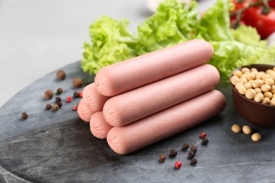 Fresh raw vegetarian sausages, lettuce and soybeans on grey board, closeup