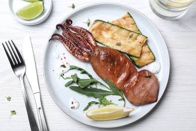Delicious grilled squid served on white wooden table, flat lay