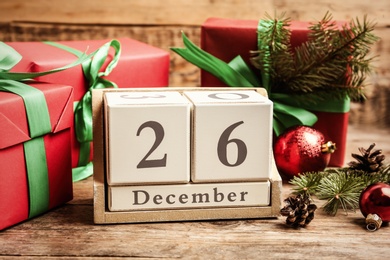 Block calendar with Boxing Day date near gifts on wooden table