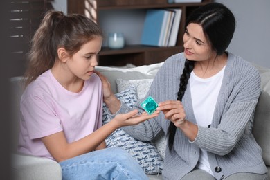 Mother giving condom to her teenage daughter at home. Sex education concept