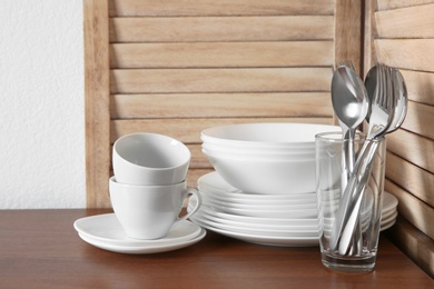 Set of clean dishes and cutlery on table in kitchen