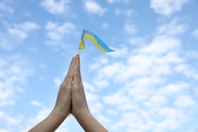 Woman holding national flag of Ukraine under blue sky with clouds, closeup. Space for text