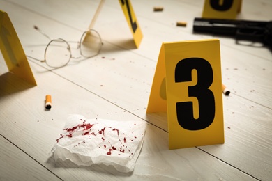 Evidences and crime scene marker on white wooden table