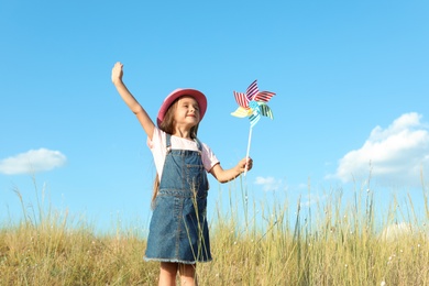 Cute little girl with pinwheel outdoors. Child spending time in nature