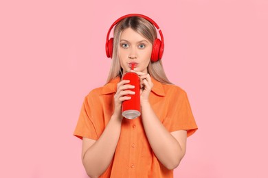 Photo of Beautiful woman drinking from red beverage can on pink background