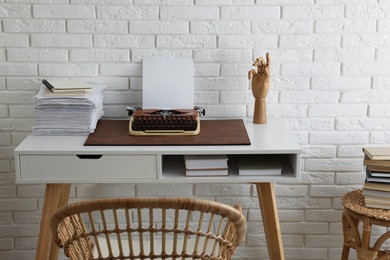 Comfortable writer's workplace with typewriter on desk near white brick wall