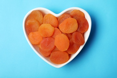 Bowl with dried apricots on color background, top view. Healthy fruit