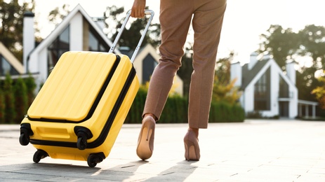 Woman with yellow suitcase outdoors. Moving day