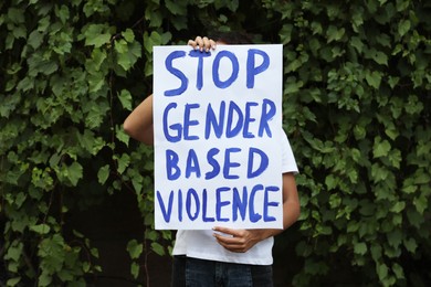 Woman holding sign with text Stop gender based violence outdoors