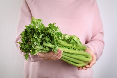Woman holding fresh green celery on white background, closeup