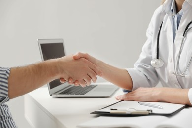 Photo of Doctor shaking hands with patient in hospital, closeup