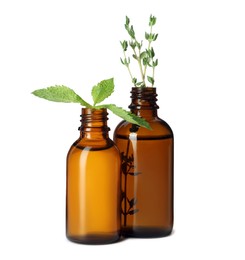 Bottles of essential oil with mint and thyme isolated on white