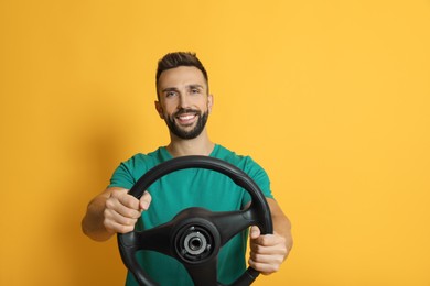 Happy man with steering wheel on yellow background