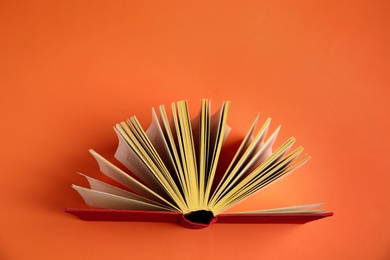 Hardcover book on orange background, top view