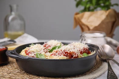 Delicious pasta with tomato sauce, basil and parmesan cheese on wicker mat