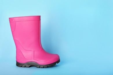 Bright pink rubber boot on light blue background. Space for text