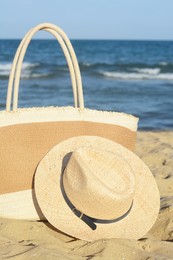 Stylish bag and hat near sea on sunny day. Beach accessories