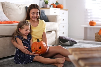 Mother and daughter with pumpkin jack o'lantern at home. Halloween celebration