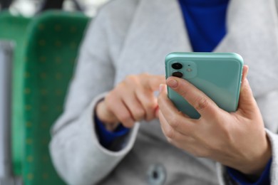 Woman using smartphone in public transport, closeup