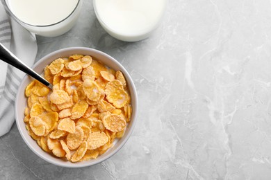 Tasty cornflakes with milk served on grey marble table, flat lay. Space for text
