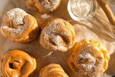 Photo of Delicious profiteroles with powdered sugar on table, top view