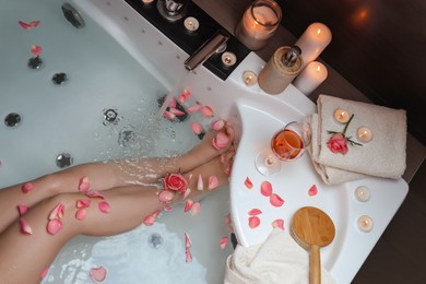 Woman taking bath with rose petals, above view. Romantic atmosphere