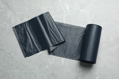 Photo of Roll of black garbage bags on light grey marble table, top view