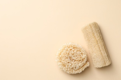 Natural shower loofah sponges on beige background, flat lay. Space for text