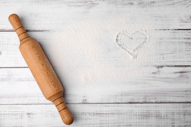 Flour and rolling pin on white wooden table, top view