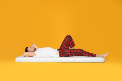 Photo of Man resting on soft mattress against orange background