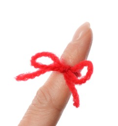 Woman showing index finger with tied red bow as reminder on white background, closeup