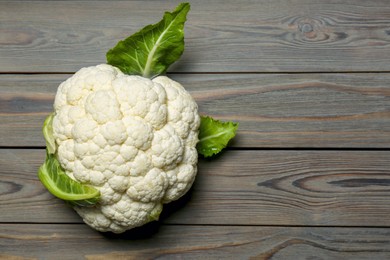 Photo of Whole fresh raw cauliflower on wooden table, top view. Space for text