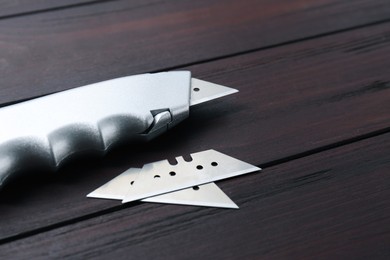 Utility knife and blades on wooden table, closeup. Space for text