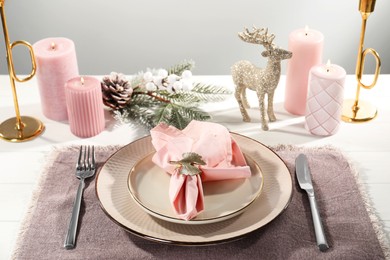 Stylish table setting with pink fabric napkin, beautiful decorative ring and festive decor on white wooden background