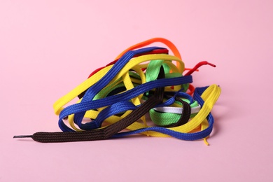 Many colorful shoe laces on light pink background