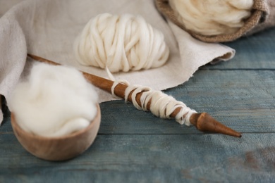 Soft white wool and spindle on blue wooden table