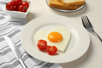 Heart shaped fried egg served on white wooden table