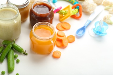 Jars with tasty baby food on white background